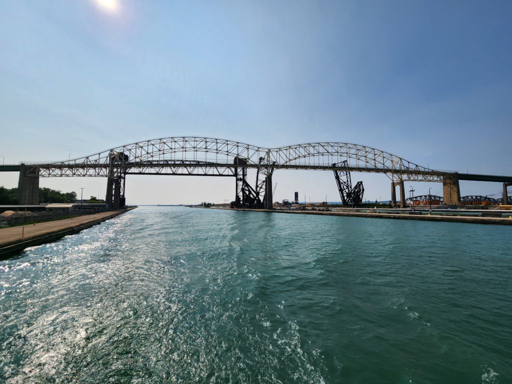 Two sections of the International Bridge over water, with blue sky above.