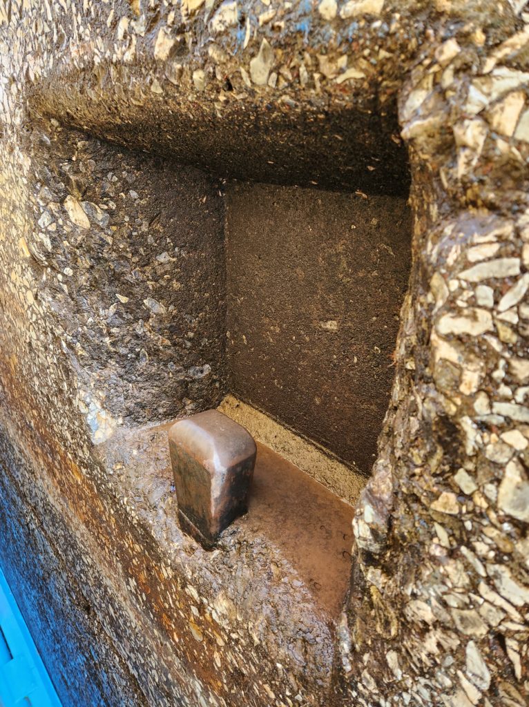 A metal tie off point in, for a boat, in the middle of a rock wall.