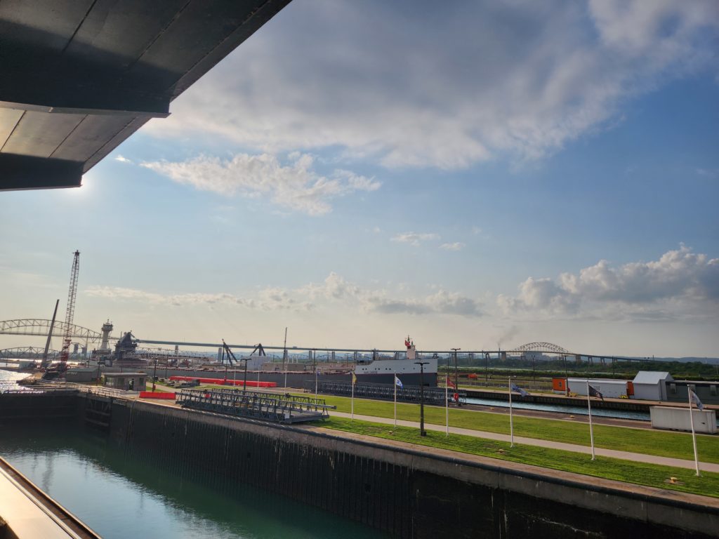 A view from the Observation Tower at the Soo Locks. Two of the locks, and several bridges in the background. The sky, with a few clouds, at the top.