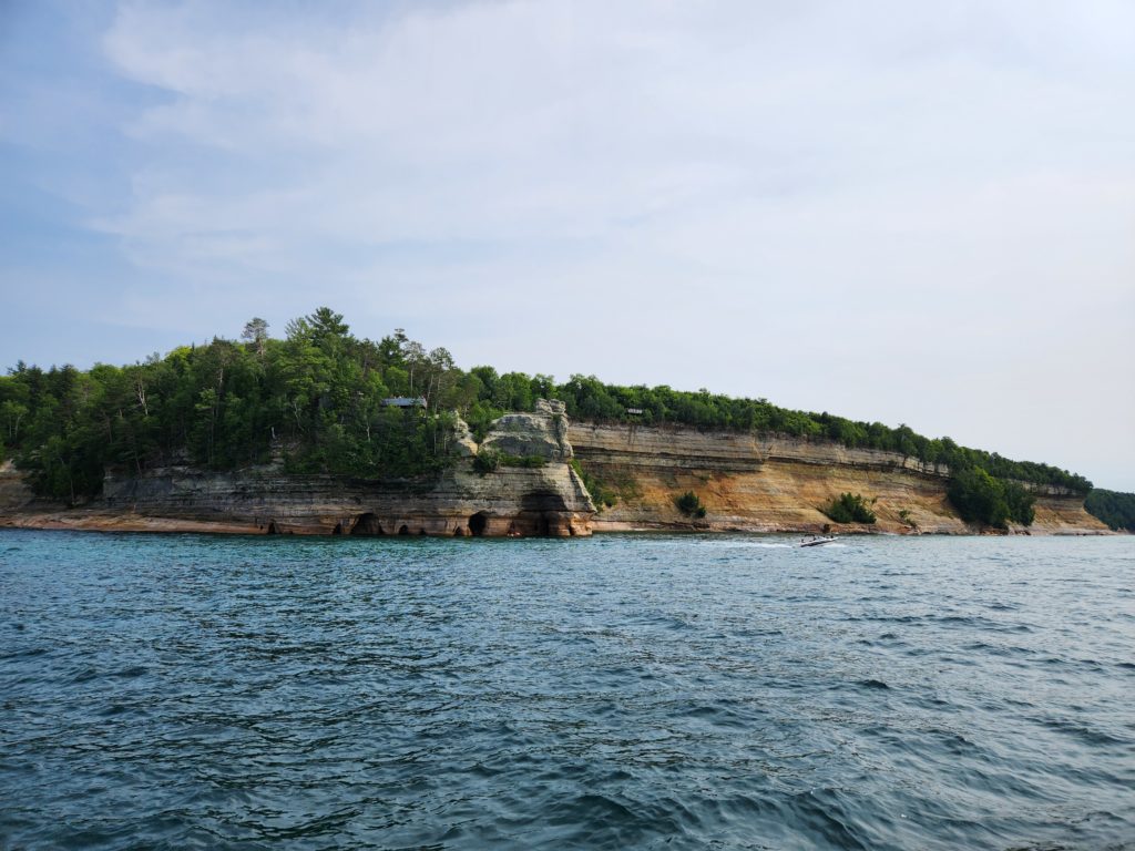 A view of the Pictured Rocks National Lakeshore from the perspective of a boat out on the water. 