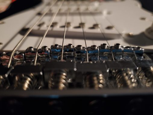 The Benefits of Learning Something New, like how to play the guitar or how to take better photos. This photo is of a guitar - a close up from the bottom of the strings looking up towards the top.